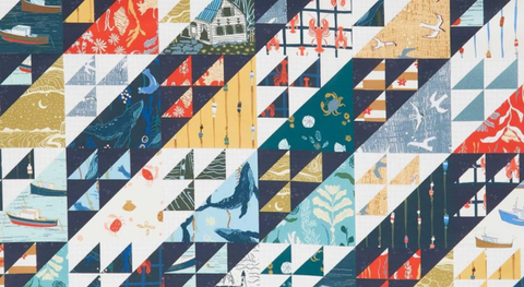 Cotton whole cloth "cheater" print with a nautical theme in a navy, red, gold, and green palette.